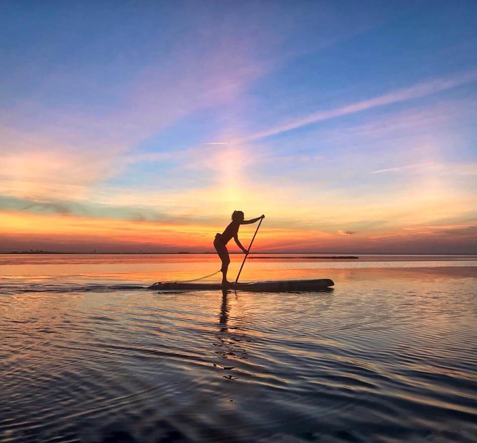 Erica Joy West paddleboarding at sunset